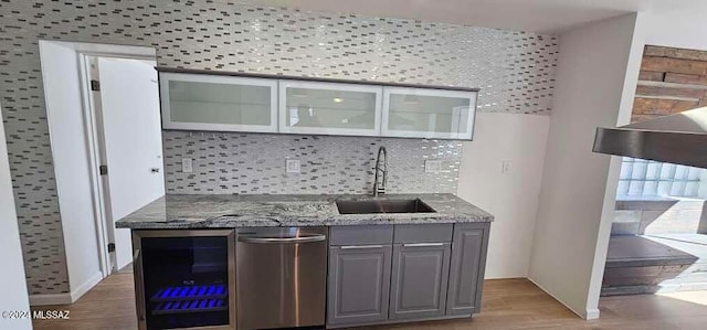 bar with gray cabinetry, light wood-type flooring, sink, stainless steel dishwasher, and beverage cooler