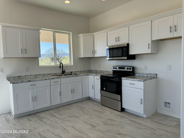 kitchen featuring light stone countertops, white cabinets, appliances with stainless steel finishes, and sink