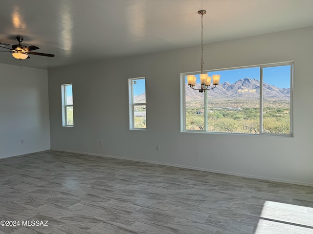 spare room featuring ceiling fan with notable chandelier and a mountain view