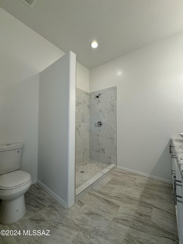 bathroom featuring toilet, a tile shower, and vanity