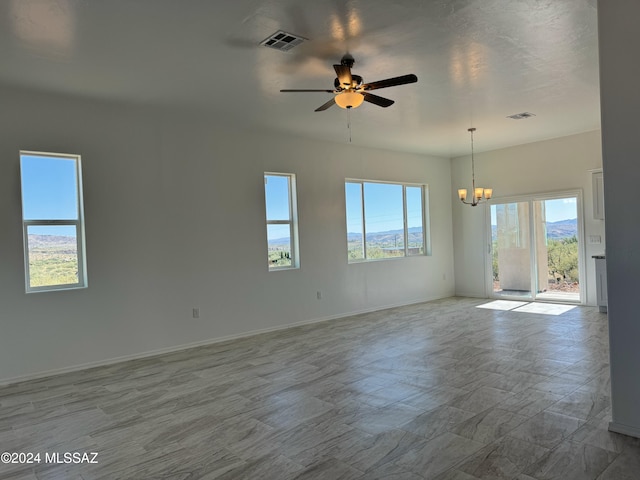 spare room featuring ceiling fan with notable chandelier