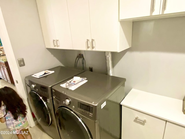 washroom with cabinets, light tile patterned floors, and washer and clothes dryer