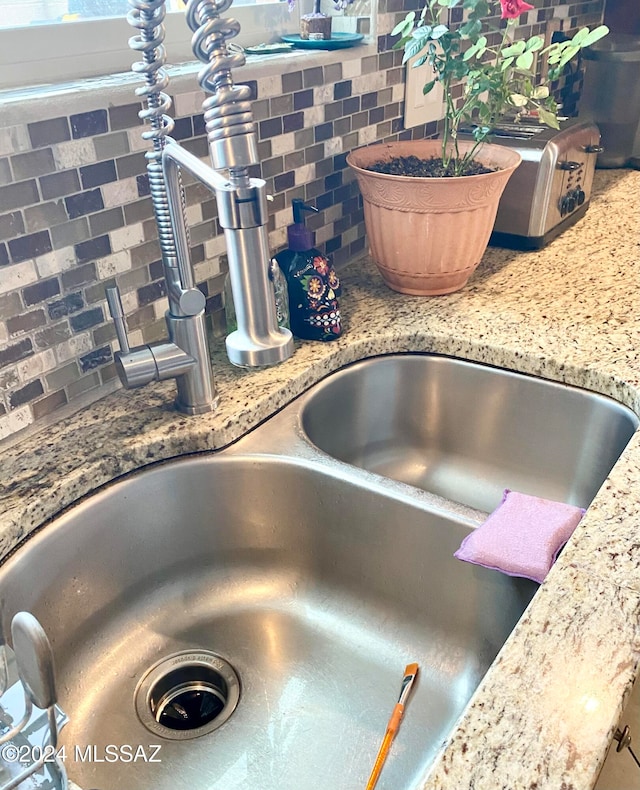 details with sink, stone counters, and tasteful backsplash