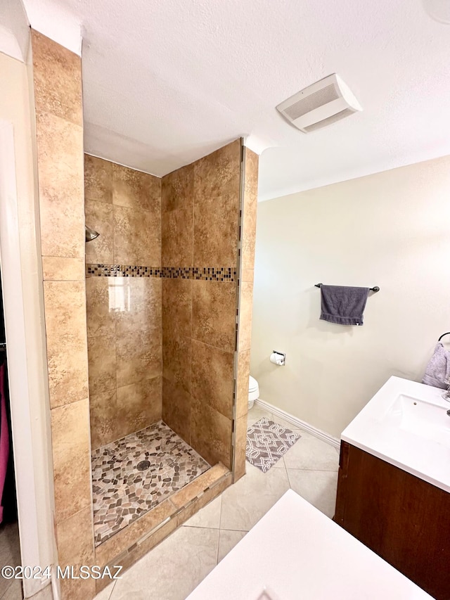 bathroom with a tile shower, tile patterned flooring, vanity, and a textured ceiling