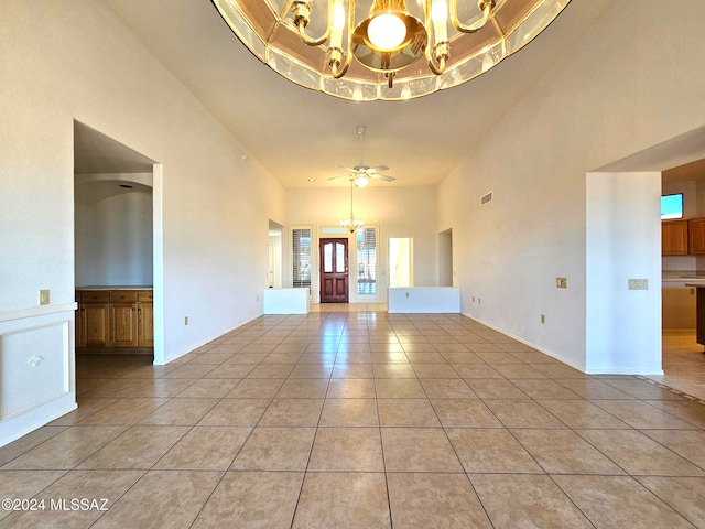 interior space featuring a towering ceiling, ceiling fan with notable chandelier, and light tile patterned floors