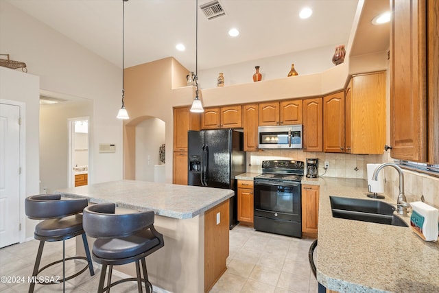 kitchen featuring a breakfast bar, a center island, black appliances, sink, and decorative light fixtures