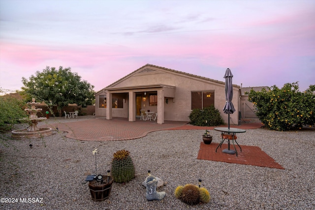 back house at dusk with a patio area