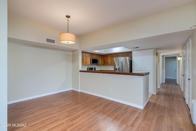 kitchen featuring stainless steel appliances, light wood finished floors, visible vents, and baseboards