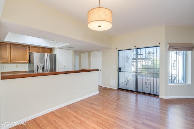 unfurnished living room with lofted ceiling, light wood finished floors, and baseboards