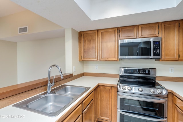 kitchen with light countertops, appliances with stainless steel finishes, a sink, and visible vents