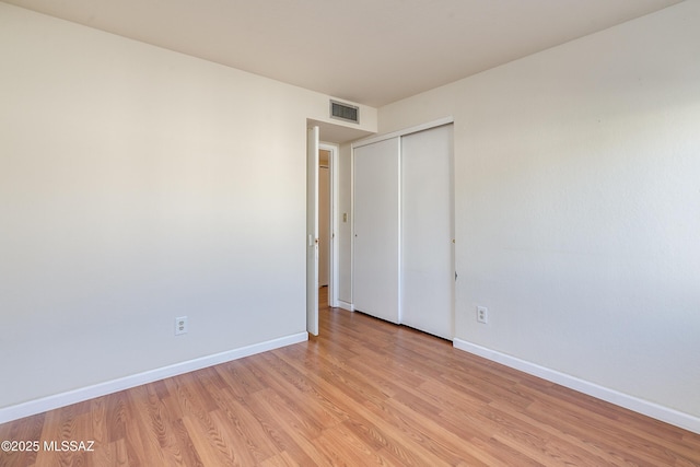 spare room with light wood-style floors, visible vents, and baseboards