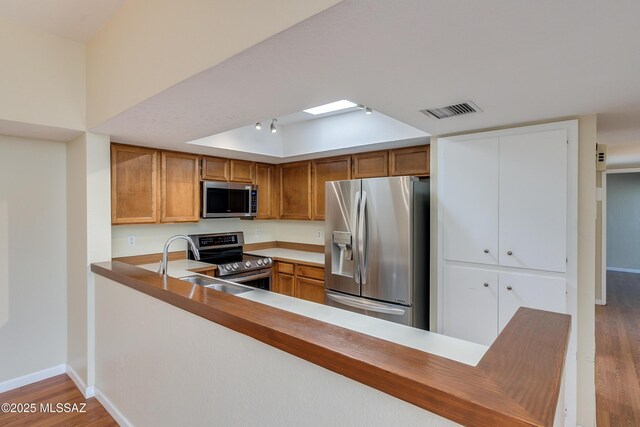 kitchen featuring kitchen peninsula, hardwood / wood-style flooring, and appliances with stainless steel finishes