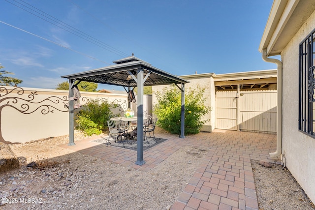 view of patio featuring outdoor dining area, a fenced backyard, and a gazebo