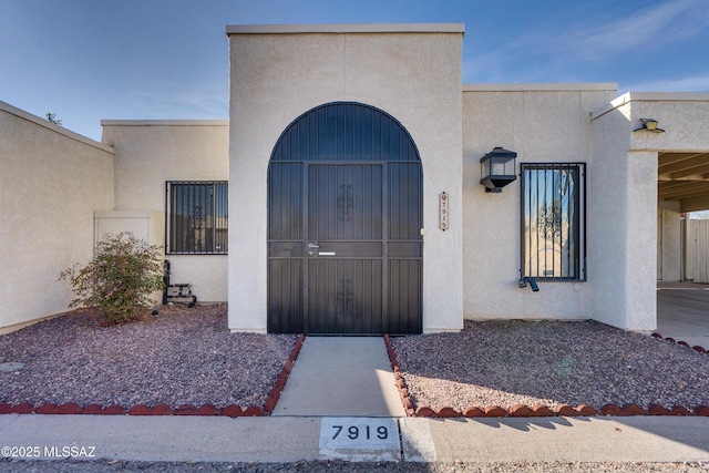 doorway to property with fence and stucco siding