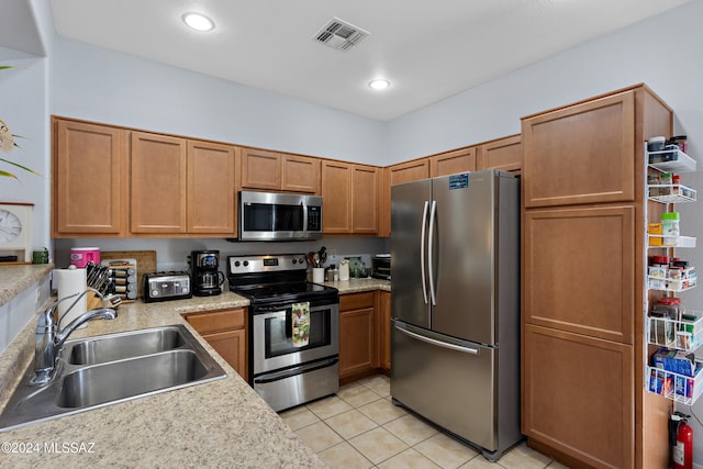 kitchen with appliances with stainless steel finishes, sink, and light tile patterned floors