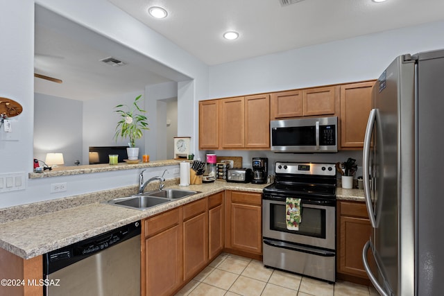 kitchen featuring stainless steel appliances, light tile patterned floors, sink, and kitchen peninsula