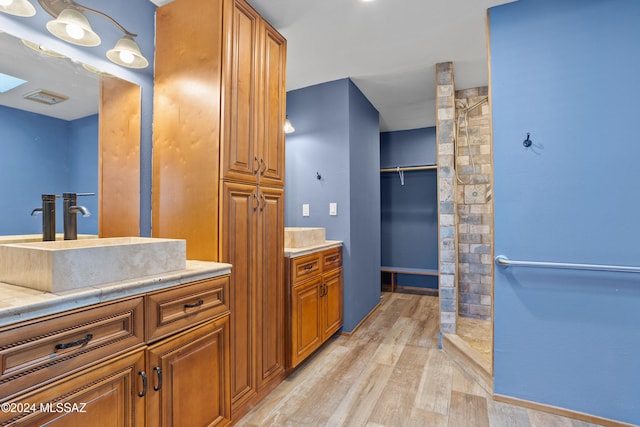 bathroom with wood-type flooring, vanity, and walk in shower