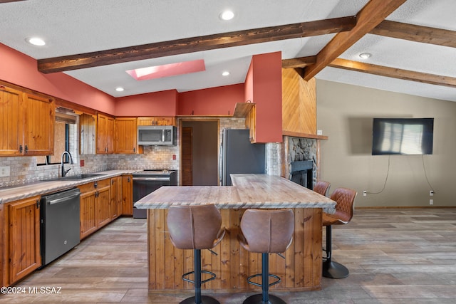 kitchen with a kitchen breakfast bar, sink, light hardwood / wood-style flooring, and appliances with stainless steel finishes