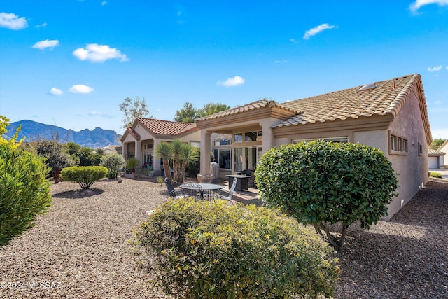 back of property with a mountain view and a patio area