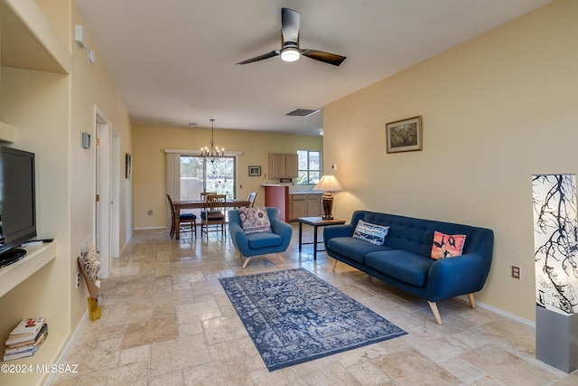 living room featuring stone tile flooring, visible vents, baseboards, and ceiling fan with notable chandelier