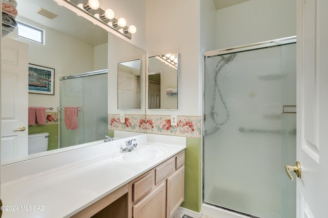 bathroom featuring vanity, toilet, and a shower with shower door