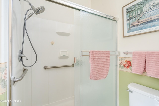 bathroom featuring toilet and a shower with door