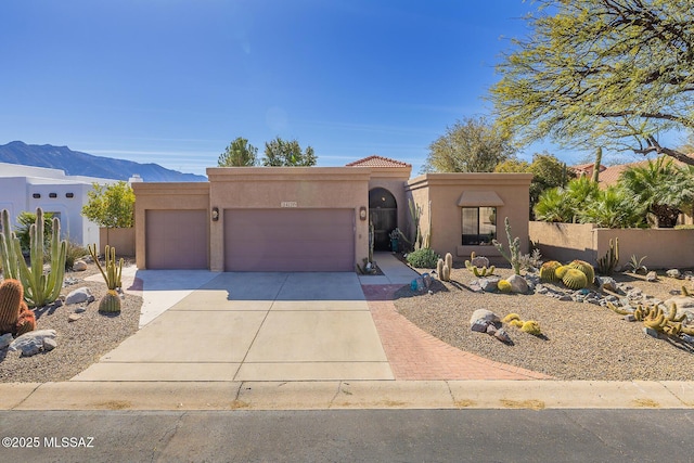 adobe home featuring a garage, driveway, a mountain view, and stucco siding