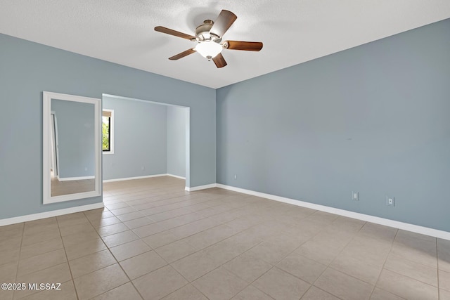 spare room with light tile patterned floors, a textured ceiling, baseboards, and a ceiling fan