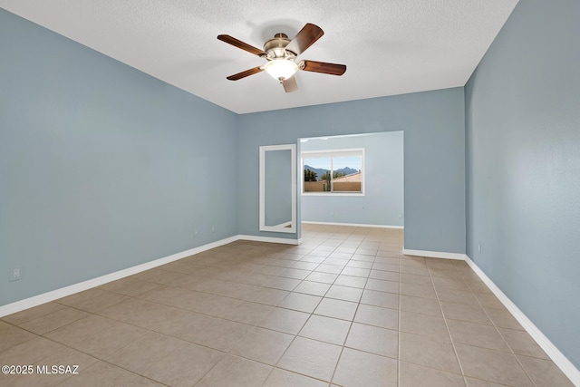 empty room featuring light tile patterned floors, a textured ceiling, baseboards, and a ceiling fan