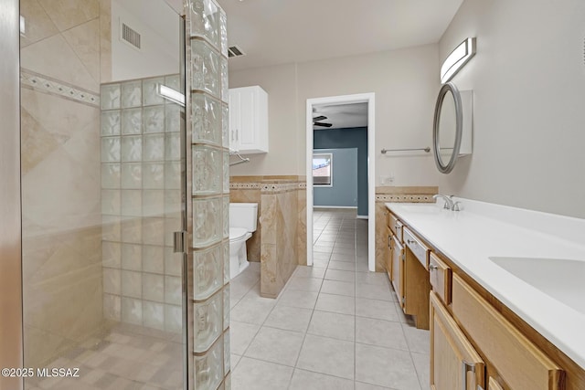 bathroom with toilet, visible vents, tile walls, tile patterned floors, and a stall shower