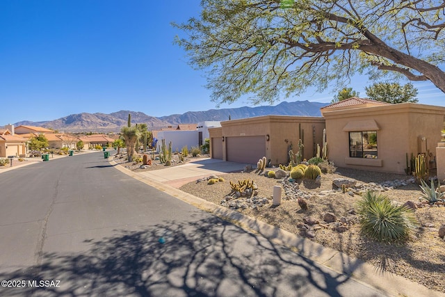 view of front facade featuring concrete driveway, a mountain view, an attached garage, and stucco siding