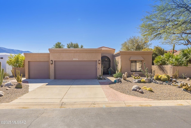 view of front of home with a garage, a mountain view, concrete driveway, and stucco siding