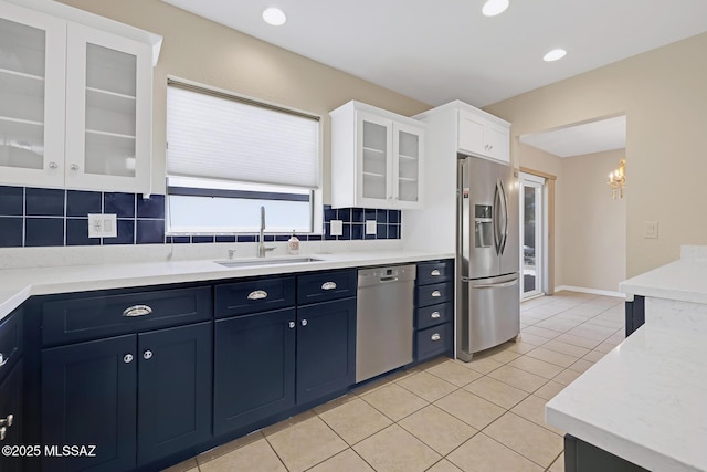 kitchen featuring light countertops, appliances with stainless steel finishes, glass insert cabinets, white cabinets, and a sink