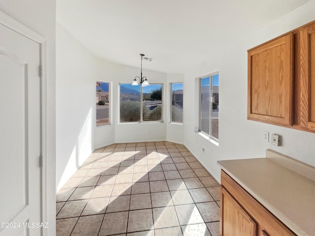 unfurnished dining area with light tile patterned floors, an inviting chandelier, and vaulted ceiling