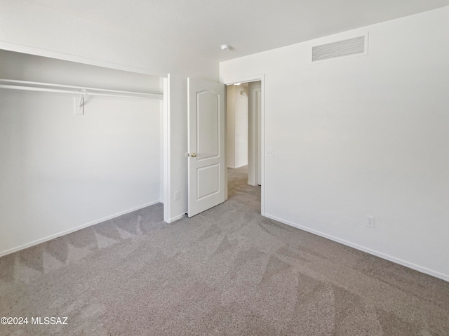 unfurnished bedroom with light carpet and a closet