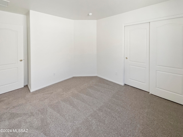 unfurnished bedroom with light carpet and a closet