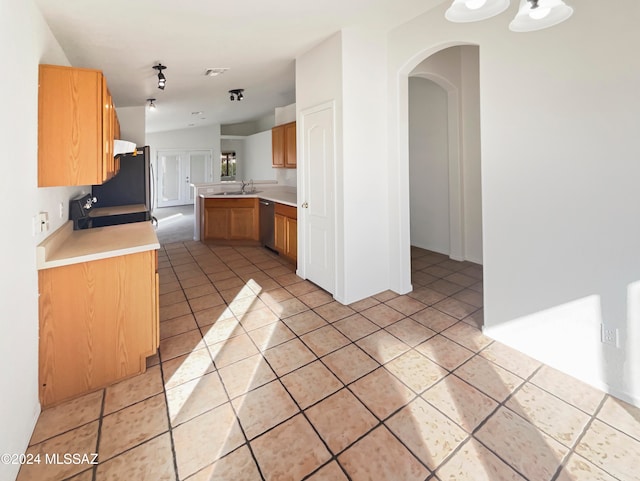 kitchen with refrigerator, dishwasher, kitchen peninsula, sink, and light tile patterned floors