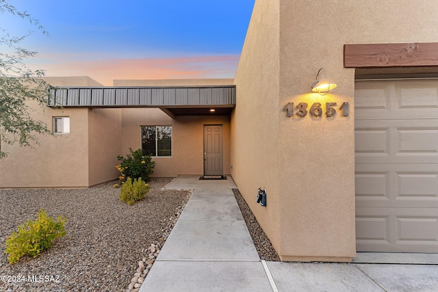 exterior entry at dusk featuring a garage