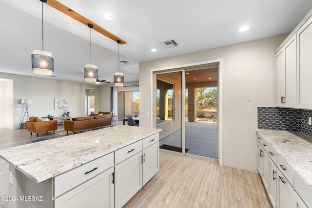 kitchen featuring white cabinets, ceiling fan, light stone countertops, tasteful backsplash, and decorative light fixtures