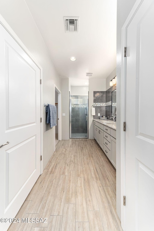 bathroom with tiled shower, vanity, and hardwood / wood-style flooring