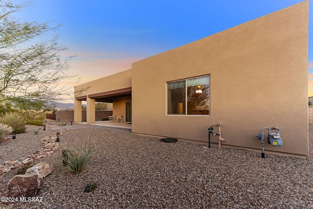 back house at dusk featuring a patio