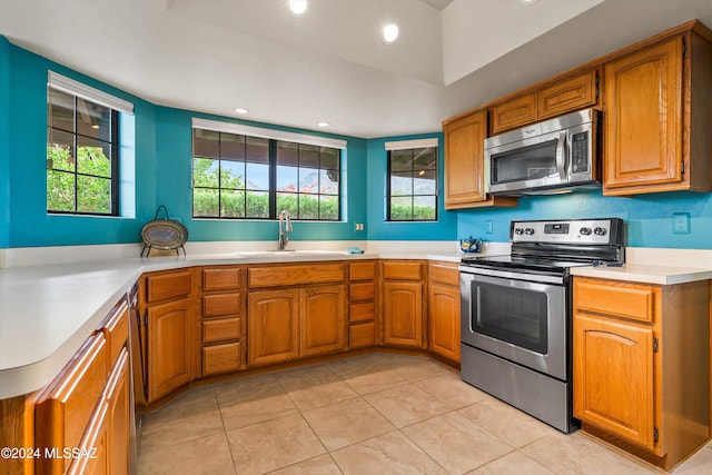 kitchen featuring light tile patterned flooring, sink, kitchen peninsula, and stainless steel appliances