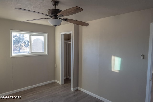 unfurnished bedroom with ceiling fan, a closet, and hardwood / wood-style flooring