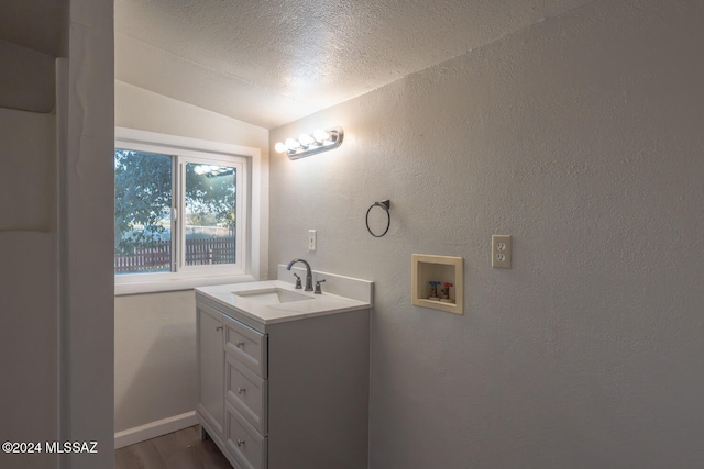 bathroom featuring vaulted ceiling, vanity, a textured ceiling, and hardwood / wood-style flooring