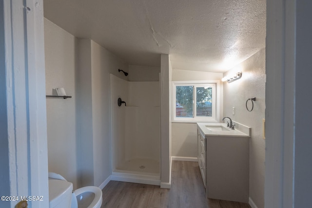 bathroom with walk in shower, vanity, a textured ceiling, wood-type flooring, and toilet