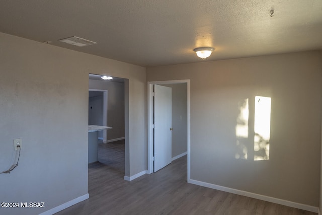 unfurnished room with a textured ceiling and dark hardwood / wood-style floors