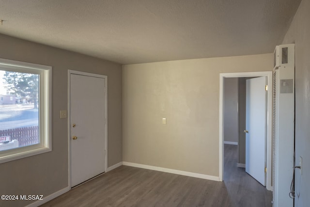 unfurnished room featuring dark hardwood / wood-style flooring and a textured ceiling