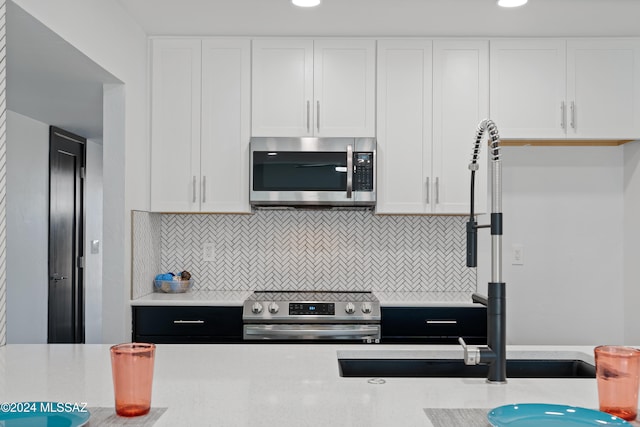 kitchen with sink, white cabinets, decorative backsplash, and stainless steel appliances