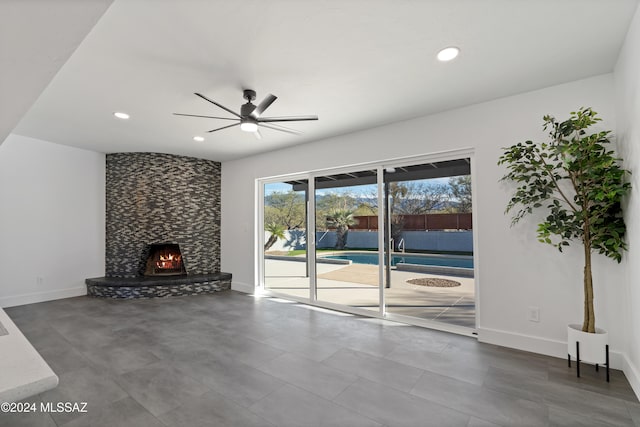 unfurnished living room featuring ceiling fan and a fireplace