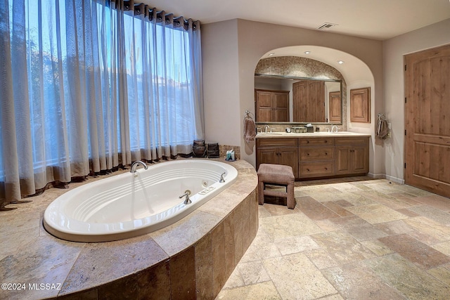 bathroom with vanity and a relaxing tiled tub